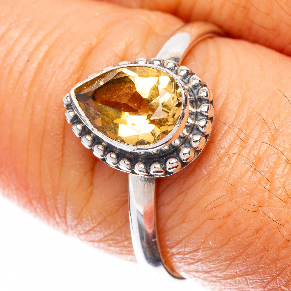 Close-up sterling silver ring with pear-shaped faceted citrine and bead-like halo prongs