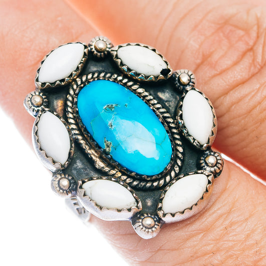 Turquoise statement ring with oval blue center stone, white insets, and dark metal setting