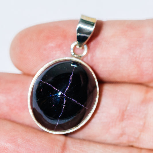 Round star garnet pendant with dark purple-red gemstone in .925 sterling silver bezel.