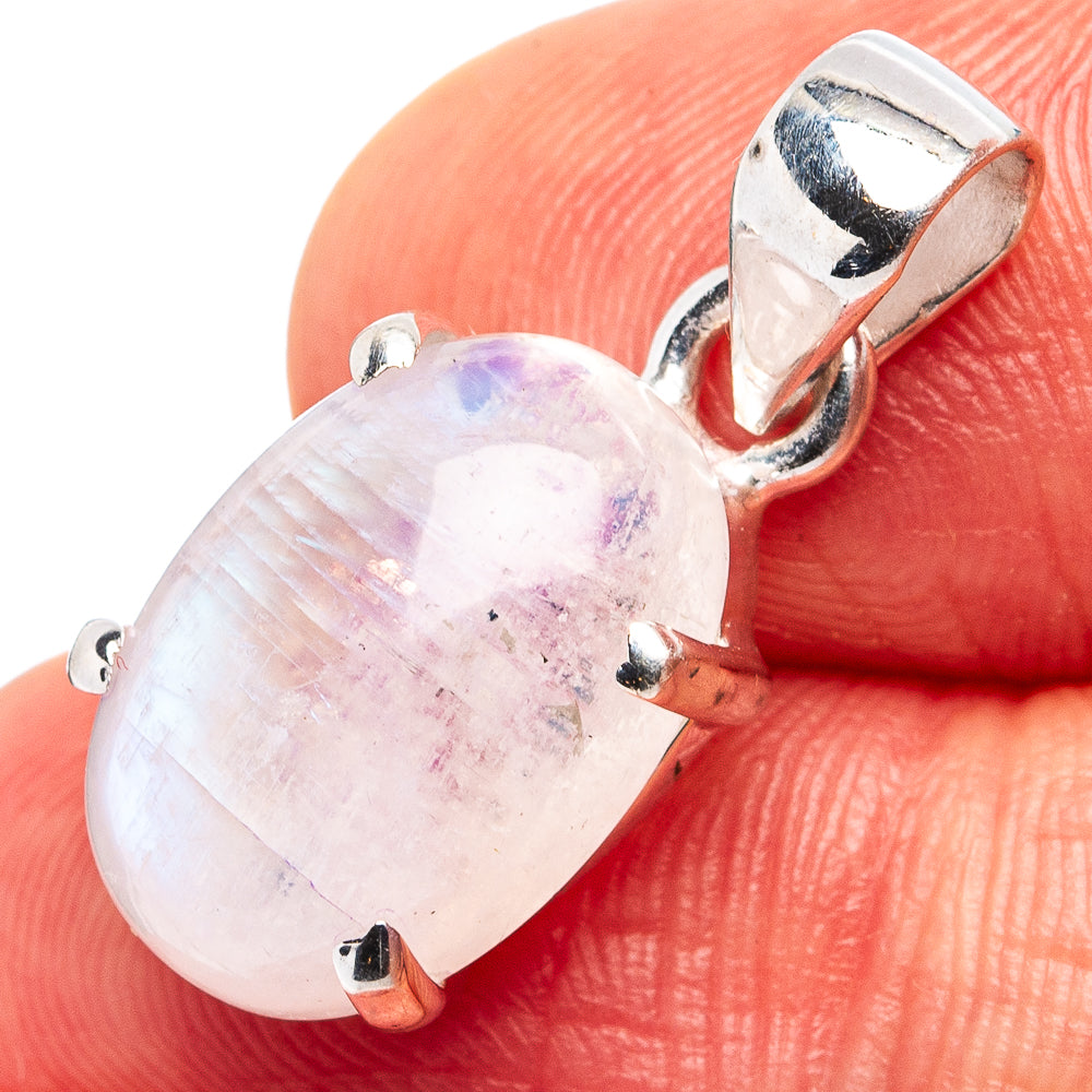 Rainbow moonstone oval pendant with silver bail and prong bezel, close-up on finger