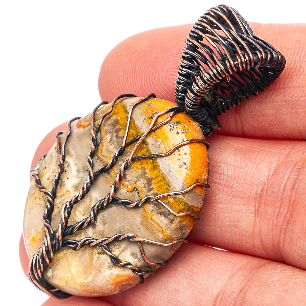 Oxidized copper wire-wrapped oval pendant with orange-yellow mottled stone.
