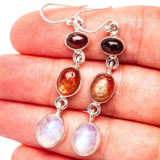 Close-up sterling silver drop earrings with red top, orange center, and white stones