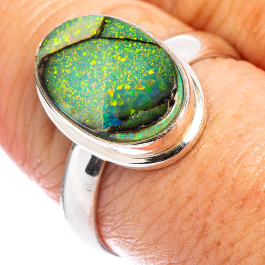 Sterling silver opal ring on finger, oval bright green and orange iridescent stone setting