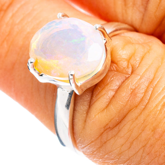 Sterling silver opal ring with oval iridescent gem and four metal prongs