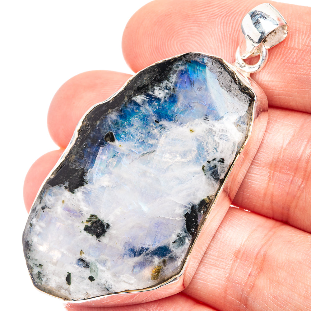 Raw rainbow moonstone pendant in silver bezel, rough stone with glowing blue flash