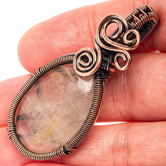 Oxidized copper wire-wrapped rutilated quartz teardrop pendant with spiral details.