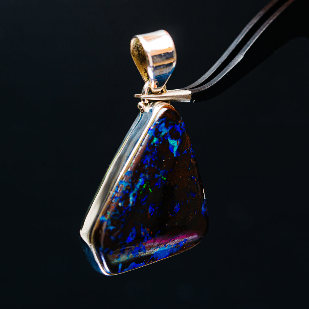 Opal boulder pendant with glowing blue-black stone and silver frame, angled view