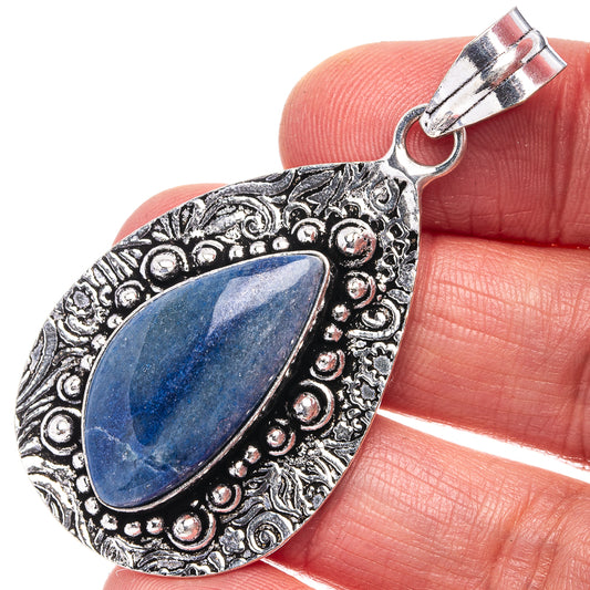 German silver pendant with ornate border and blue teardrop gemstone, top bail visible