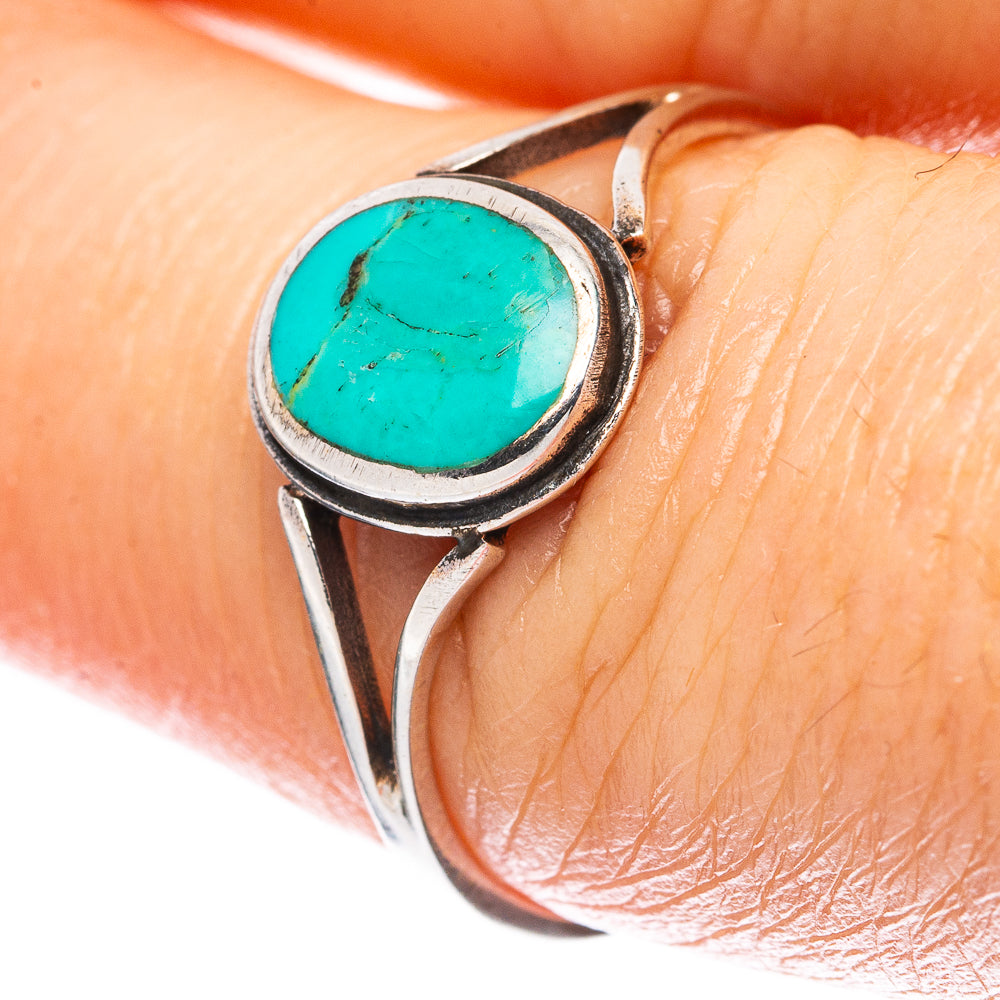 Turquoise cabochon sterling silver ring on finger, round bezel with blue-green stone