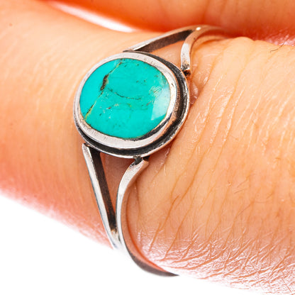 Turquoise cabochon sterling silver ring on finger, round bezel with blue-green stone