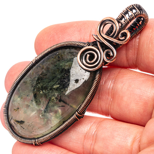 Close-up oxidized copper wire-wrap pendant with teardrop prehnite cabochon and coiled bezel