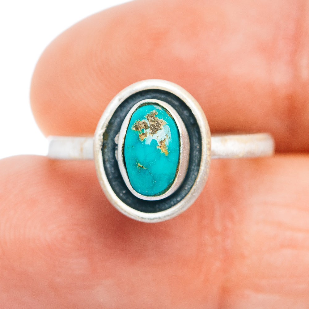 Sterling silver oval turquoise ring with black edge bezel and gold-toned stone matrix