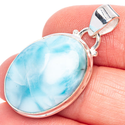 Larimar oval pendant with sterling silver bezel and top loop, close on fingers