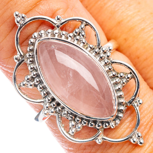Sterling silver oval rose quartz ring with ornate crown setting, close-up on finger