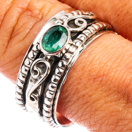 Sterling silver ring with oval green gemstone and ornate band, worn on finger