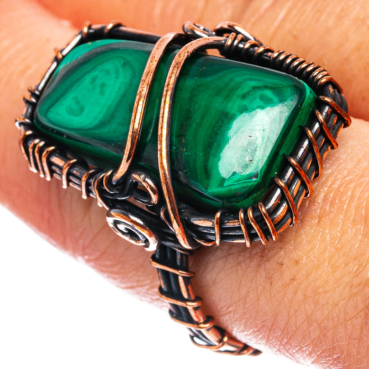 Malachite wire-wrap ring with green stone in oxidized copper frame on hand