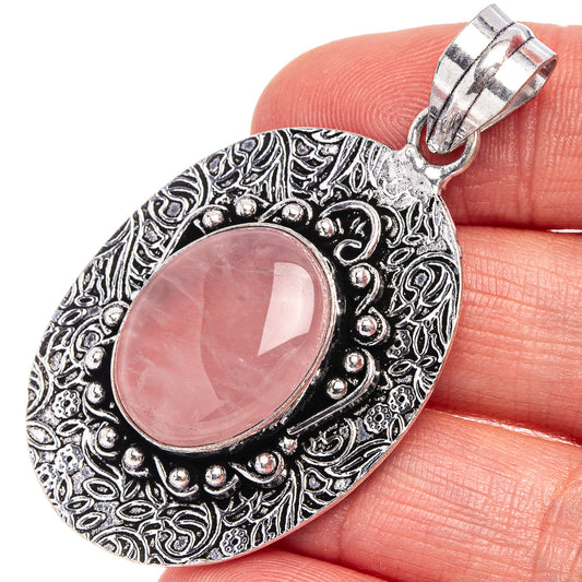 Rose quartz pendant with oval pink stone, ornate silver-tone bezel and bail