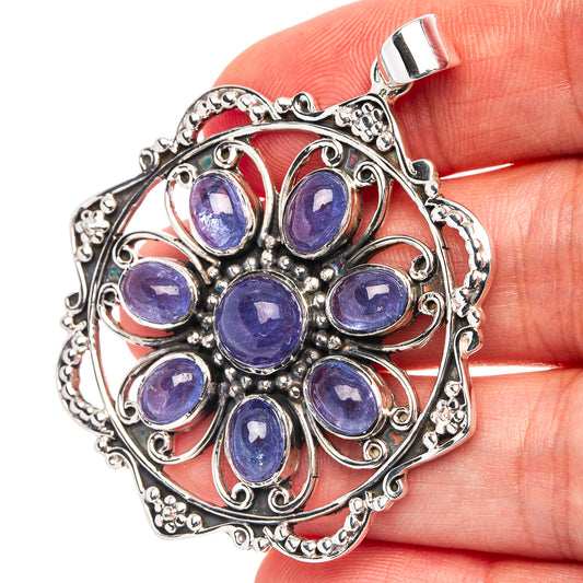 Sterling silver tanzanite pendant with central round blue stone and looped filigree bail