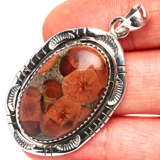 Sterling silver oval pendant with orange-brown stone in ornate bezel setting