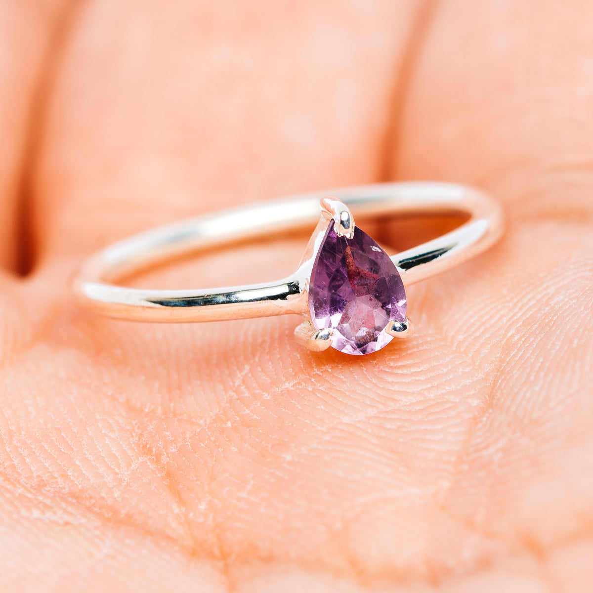 Polished sterling silver ring with pear-shaped amethyst center stone