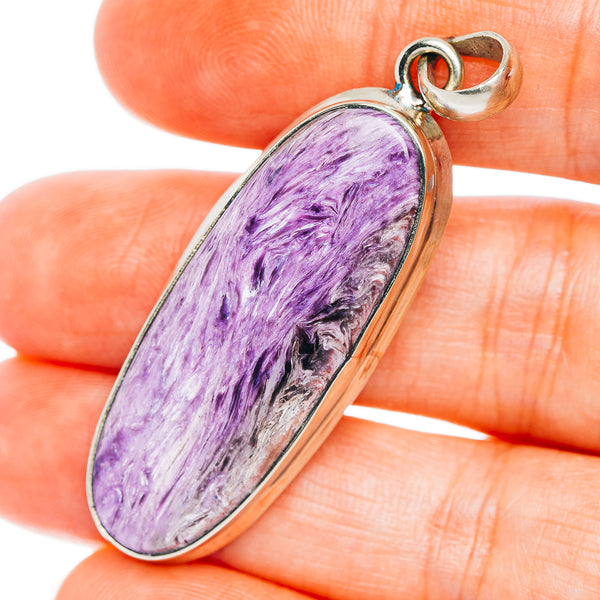 Oval charoite cabochon pendant, purple stone with silver-toned bezel and bail.