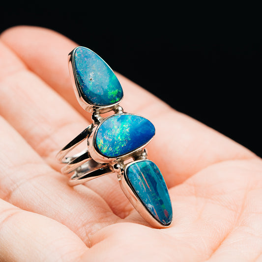 Sterling silver opal doublet ring with three blue teardrop stones, angled view