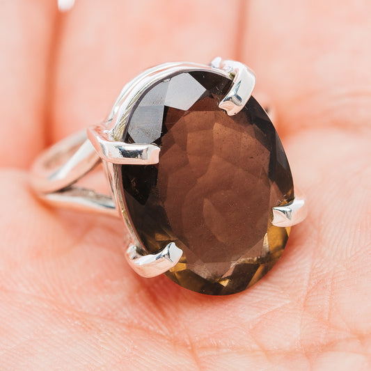 Oval faceted smoky quartz ring with silver prongs and glossy cut-stone top