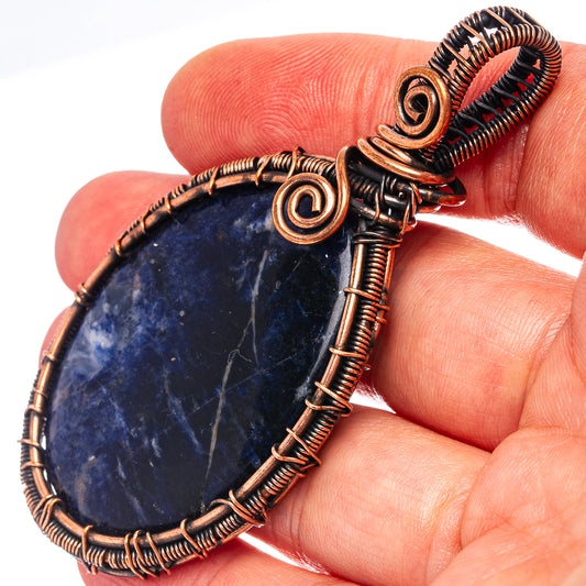 Wire-wrapped sodalite teardrop pendant with blue stone and oxidized copper swirl detail