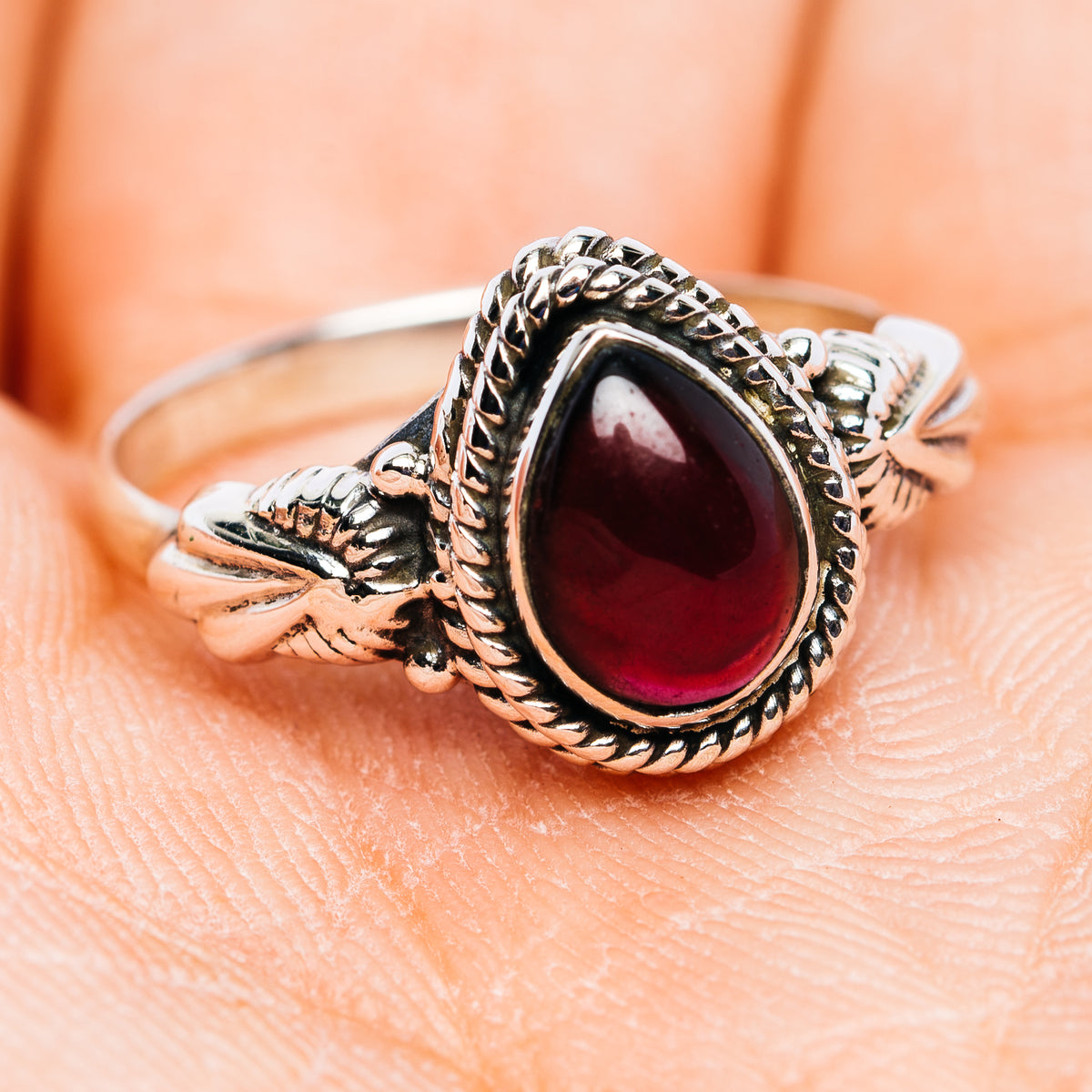 Sterling silver dainty ring with oval dark red garnet and detailed braided band
