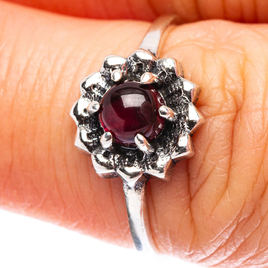 Sterling silver ring with round garnet centerpiece and ornate halo of stones