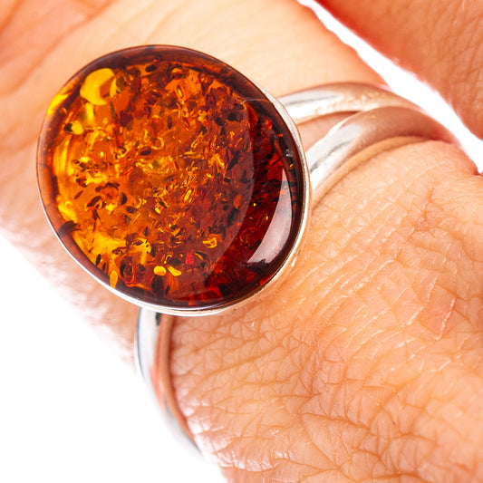 Amber oval ring with silver bezel on an adjustable band, warm honey color.
