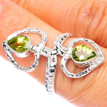 Sterling silver ring with two heart settings and peridot green gemstones close-up
