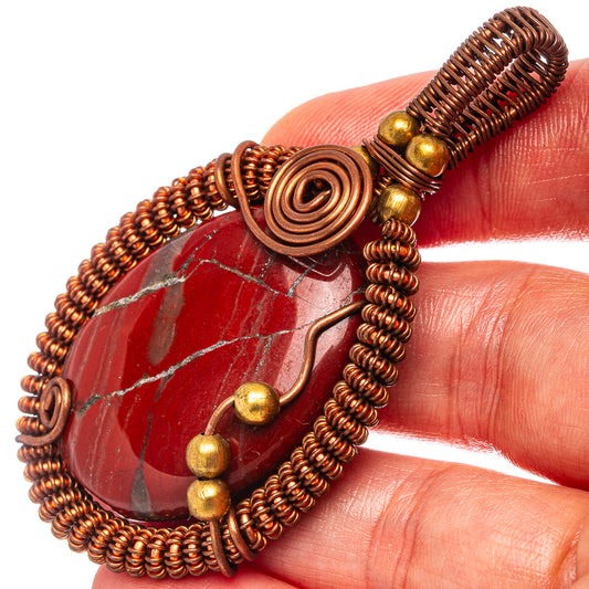 Red jasper wire-wrap pendant close-up with copper spiral bezel and wire loops