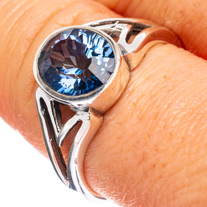 Sterling silver ring with oval blue gemstone and cutout scroll band