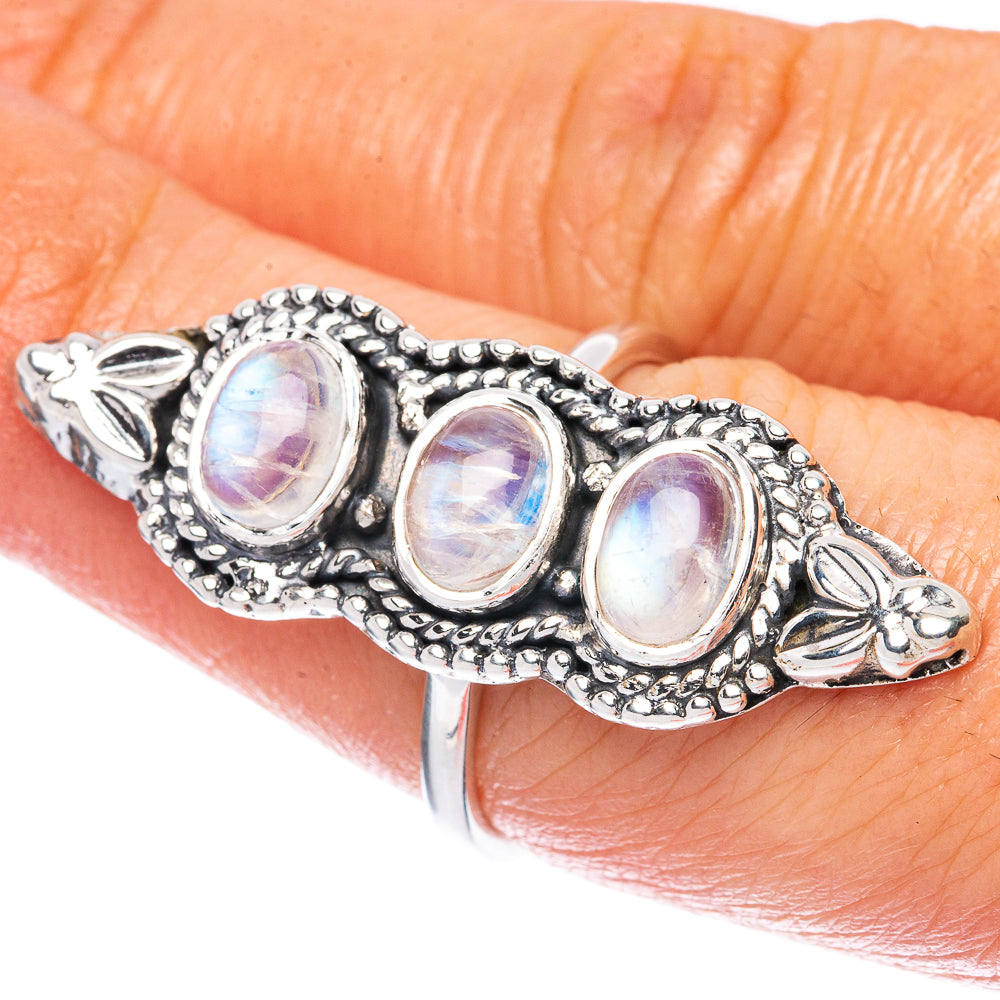 Sterling silver moonstone ring on finger, three oval opalescent stones with filigree