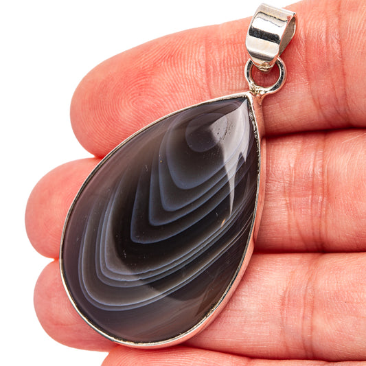 Sterling silver Botswana agate teardrop pendant with dark banded stone, bail at top