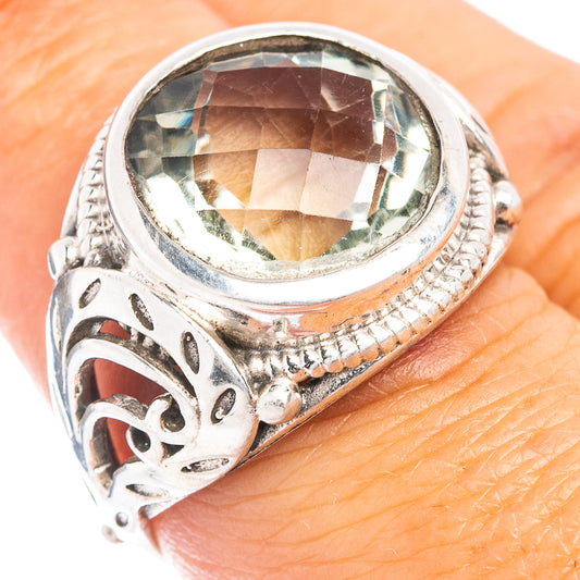 Sterling silver ring with oval green amethyst center and ornate carved side details.