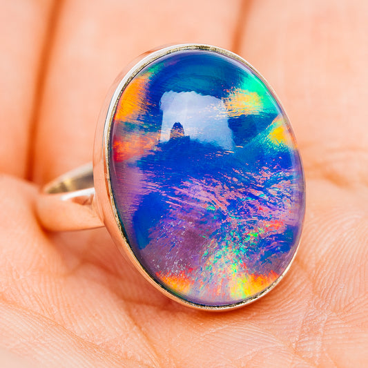Oval iridescent opal sterling silver ring with slim band, close-up on finger
