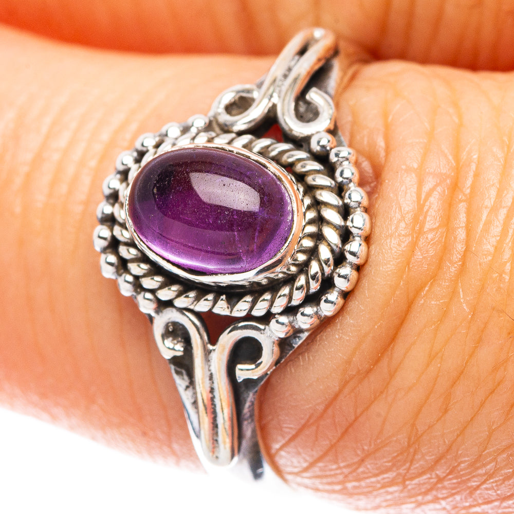 Sterling silver amethyst ring on fingertip, oval purple gemstone with raised beaded border