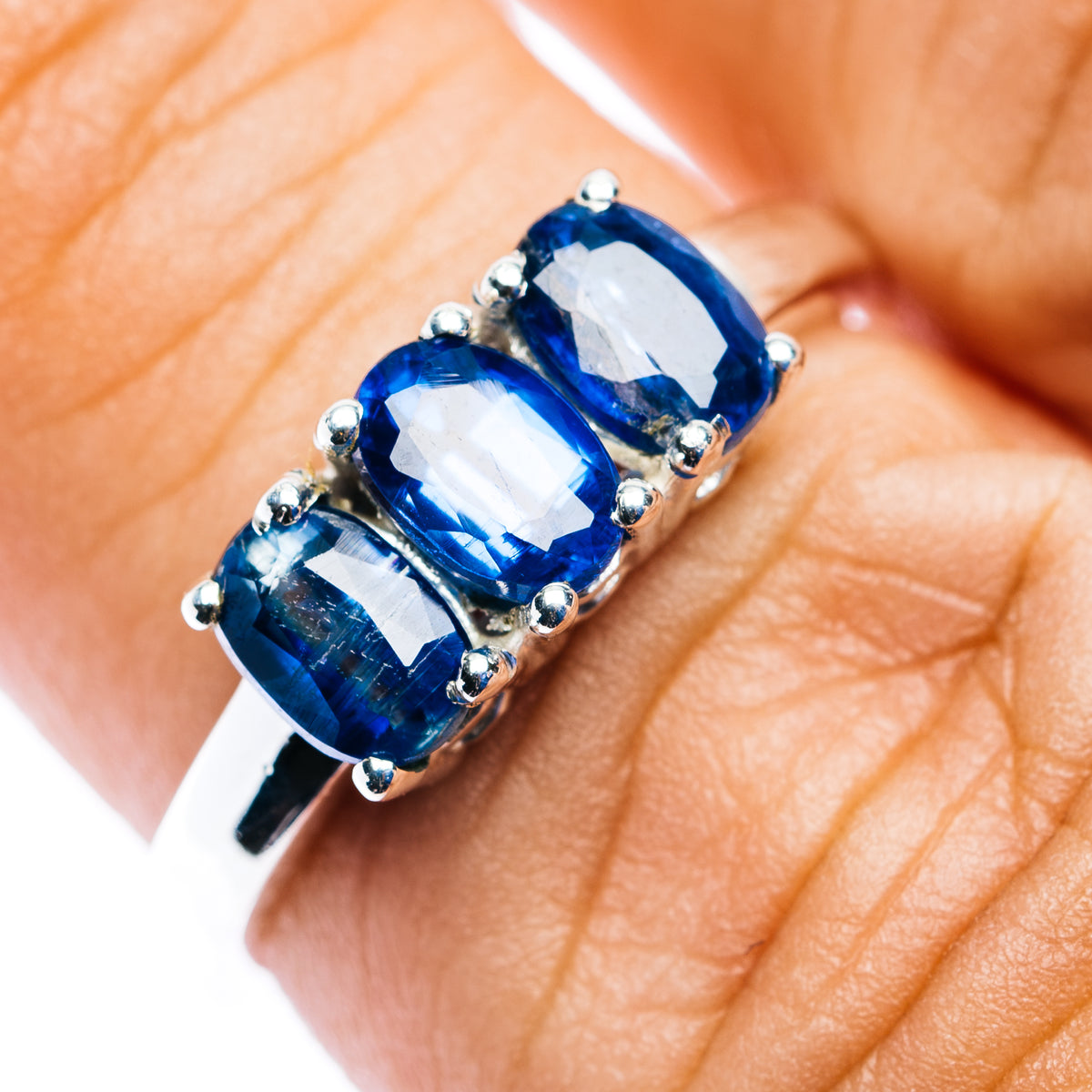 Three-stone kyanite ring with three dark-blue stones in silver prong setting