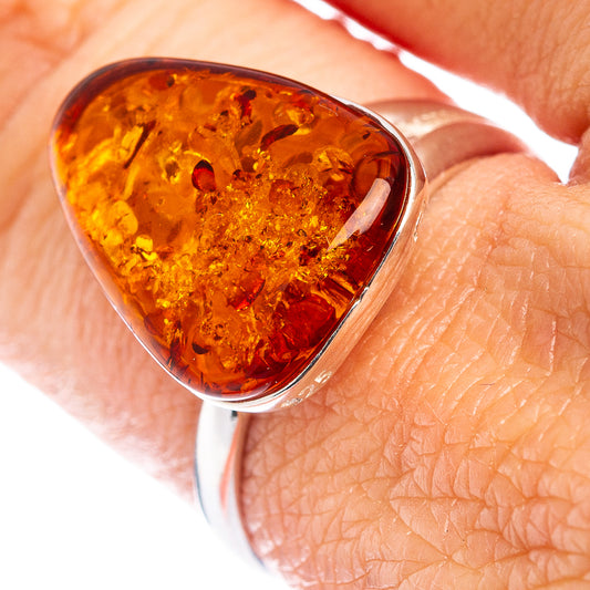 Amber teardrop ring with silver bezel setting on a finger