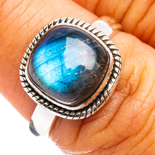 Oval labradorite sterling silver ring with blue flash and engraved bezel on finger
