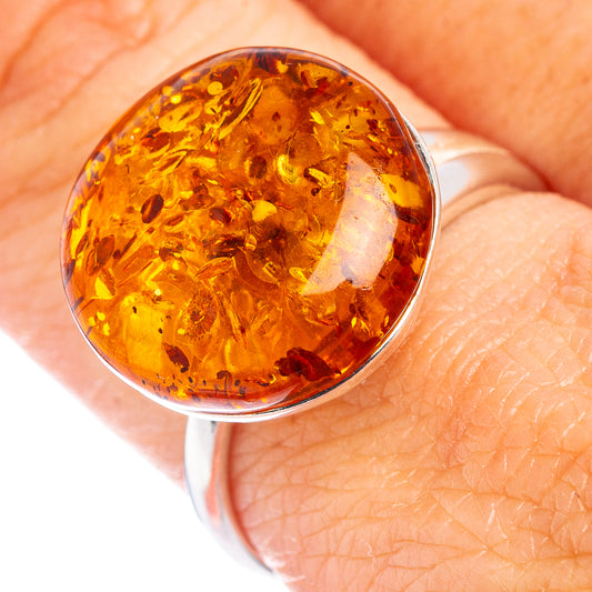 Amber cabochon sterling silver adjustable ring on finger, oval warm orange stone