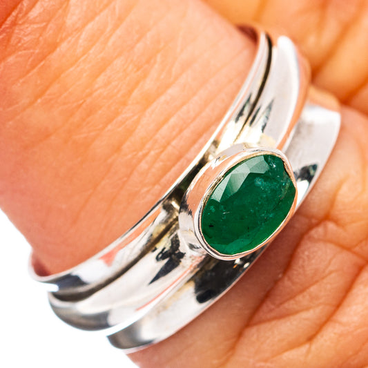 Sterling silver spinner ring with oval green gemstone bezel, close-up on hand