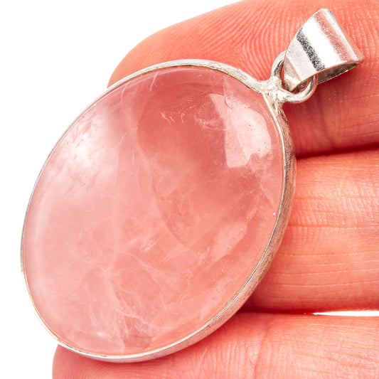 Rose quartz oval pendant on fingertip, silver-plated bail and pink cabochon