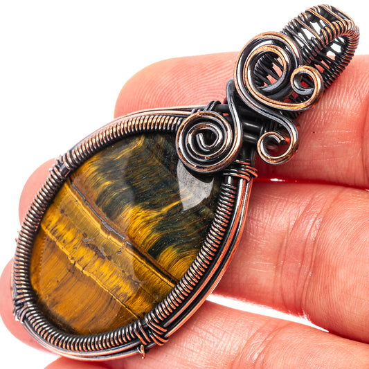 Oval tiger’s eye pendant in oxidized copper wire with stacked spiral rings, close-up