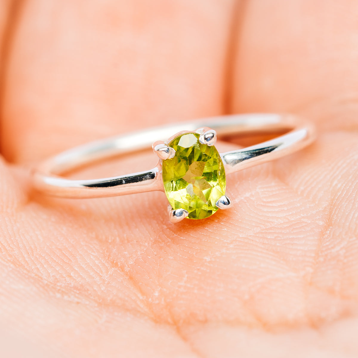 Peridot green oval ring with four-prong setting on .925 sterling silver band