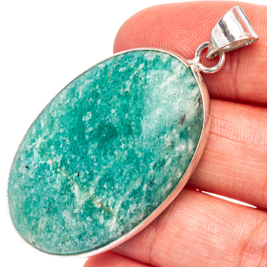 Amazonite pendant in silver-plated oval setting, held on a finger