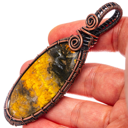 Wire-wrapped teardrop jasper pendant with yellow-and-dark stone, oxidized copper coils