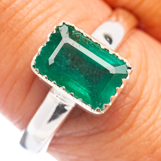 Silver bezel-set dark green emerald cushion with faceted highlights, close-up prongs